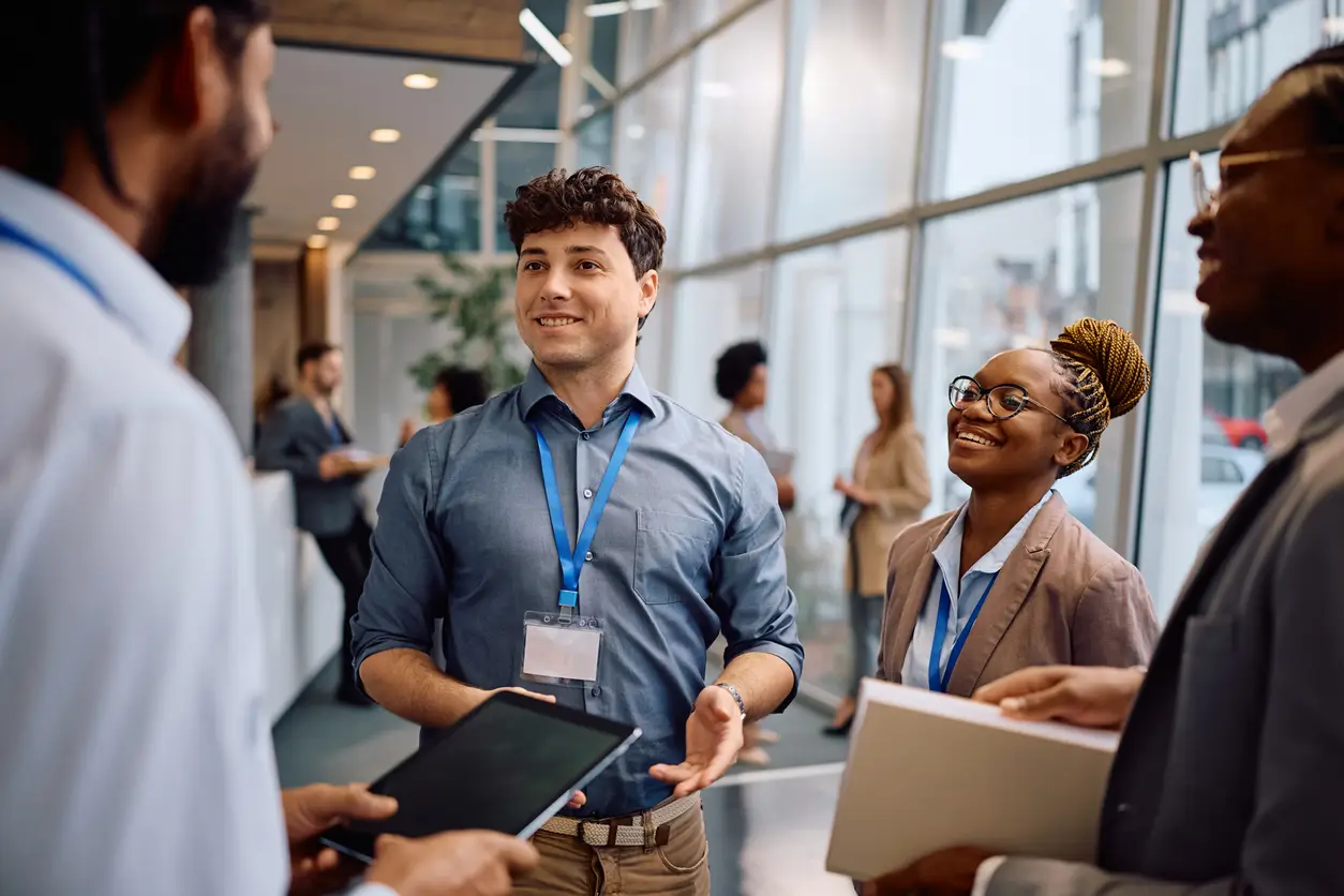 Happy businessman talking to his colleagues in hallway of a convention center.