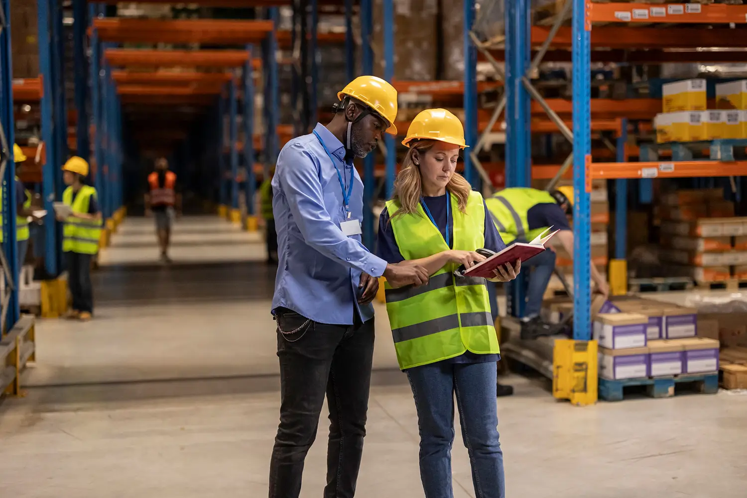 Warehouse workers checking inventory using a notebook